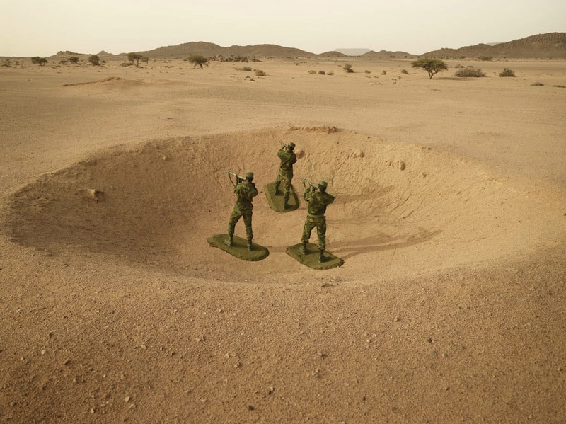 Polisario Soldiers stand posed as toy soldiers in a bomb crater from the conflict
